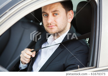 Man puts on a safety belt in a new car. Man puts on a safety belt in a new car. 61678373