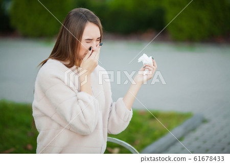 Cold and flu. Upset woman with flu and tissues on outdoor Cold and flu. Upset woman with flu and tissues on outdoor 61678433