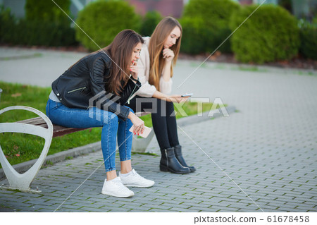 Upset women with problems sitting on a bench. 61678458