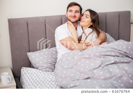 Loving couple relaxing in bed at home Loving couple relaxing in bed at home 61678764
