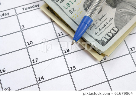 Pen and many hundred US dollar bills on calendar 61679864