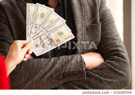 Business. Women's Hand Gives Money to Male. Woman Gives Bribe. B 61680504