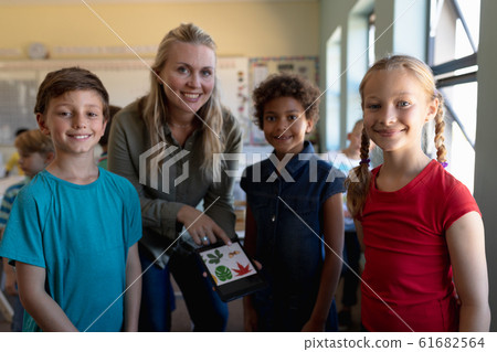 Female teacher looking to camera with a group of three schoolchildren Female teacher looking to camera with a group of three schoolchildren 61682564