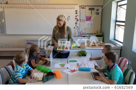 Female teacher with long blonde hair standing in a classroom 61682569