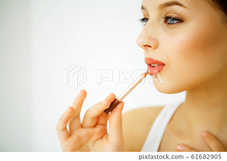 Beauty and Care. Portrait of a Young Woman with a Beautiful Skin. Beautiful Lips. Girl Holding Lipstick in her Hands. Woman with Beautiful Blue Eyes. Makeup. Care for the Lips Beauty and Care. Portrait of a Young Woman with a Beautiful Skin. Beautiful Lips. Girl Holding Lipstick in her Hands. Woman with Beautiful Blue Eyes. Makeup. Care for the Lips 61682905