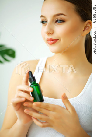 Beauty and Care. Portrait of a Young Woman with a Beautiful Skin. Girl Keeping Cream in Hands. Woman with Beautiful Blue Eyes. Cosmetics. Skin Care 61683383
