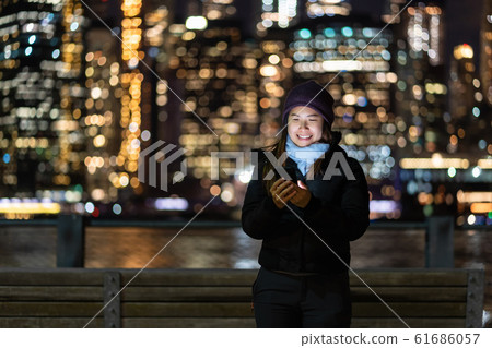 Asian woman in Winter suit using smart mobile phone with smile action over the photo blurred bokeh of New york Cityscape beside the east river background, USA downtown, career concept Asian woman in Winter suit using smart mobile phone with smile action over the photo blurred bokeh of New york Cityscape beside the east river background, USA downtown, career concept 61686057