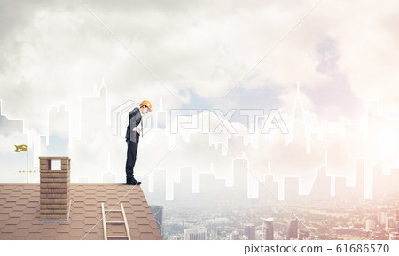Engineer man standing on roof and looking down. Mixed media 61686570