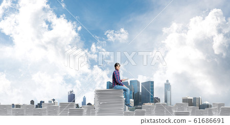 Attractive man sitting on pile of paper documents. 61686691
