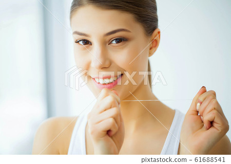 Health and Beauty. Beautiful Young Girl With White Teeth Cleans Teeth With Dental Floss. A Woman With A Beautiful Smile. Tooth Health Health and Beauty. Beautiful Young Girl With White Teeth Cleans Teeth With Dental Floss. A Woman With A Beautiful Smile. Tooth Health 61688541