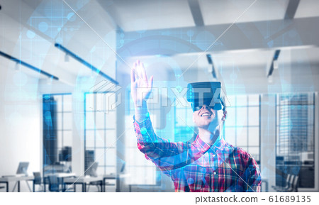 Young man in modern office interior experiencing virtual reality technology Young man in modern office interior experiencing virtual reality technology 61689135
