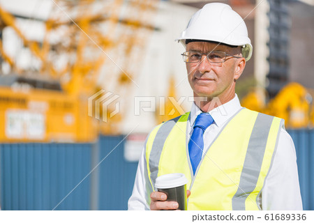 Engineer builder on construction site at sunny day with coffee in hand 61689336