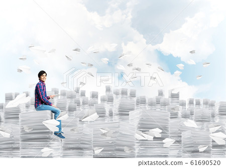 Attractive man sitting on pile of paper documents. Attractive man sitting on pile of paper documents. 61690520