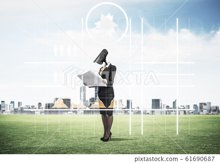 Camera headed woman standing on green grass against modern citys 61690687