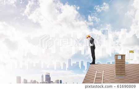 Engineer man standing on roof and looking down. Mixed media 61690809