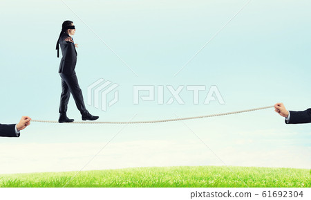 Business concept of risk support and assistance with man balancing on rope Business concept of risk support and assistance with man balancing on rope 61692304
