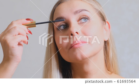 Confident happy young woman holding mascara apply on eyeleashes prepare getting ready in the morning Confident happy young woman holding mascara apply on eyeleashes prepare getting ready in the morning 61693564