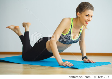 Young yogi attractive woman practicing yoga concept, wearing sportswear, black tank top and pants, full length, white loft background Young yogi attractive woman practicing yoga concept, wearing sportswear, black tank top and pants, full length, white loft background 61694203