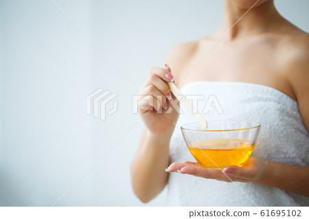Women hold orange paraffin wax bowl. Woman in beauty salon Women hold orange paraffin wax bowl. Woman in beauty salon 61695102