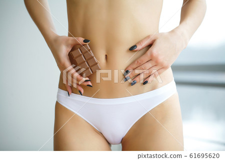 Up Of Woman Wearing Underwear Holding Slice Of Brown Chocolate And Touching Stomach 61695620