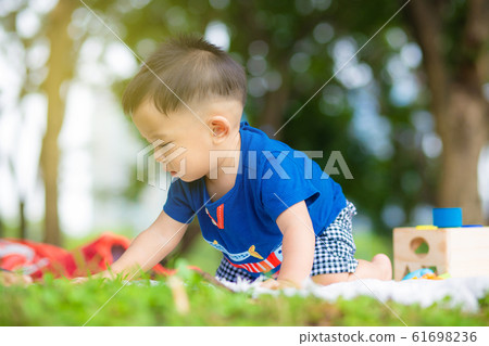 Happy infant baby boy crawling on meadow play toy Happy infant baby boy crawling on meadow play toy 61698236