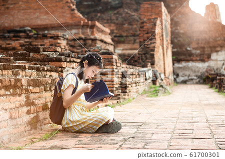 Asian cute girl relaxing outdoors while read history book,Student enjoy learning at historical, park,Wat Mahathat,Ayutthaya,Thailand Asian cute girl relaxing outdoors while read history book,Student enjoy learning at historical, park,Wat Mahathat,Ayutthaya,Thailand 61700301