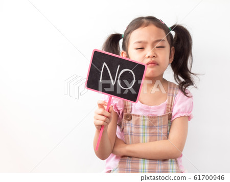 Angry little girl and raise the sign "No". The emotion of a child when displeased. Selective focus at the sign. White backdrop. 61700946