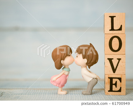 Closeup of couple cute dolls in love and kissing together with LOVE wooden block on blue wooden background. Use for valentines day, love and relationship concept. Closeup of couple cute dolls in love and kissing together with LOVE wooden block on blue wooden background. Use for valentines day, love and relationship concept. 61700949
