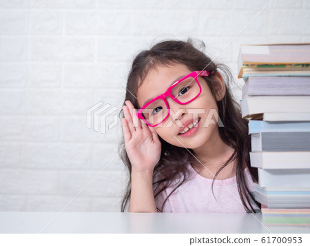 Asian little cute girl wearing pink glasses and hide and seek with a stack of books. Preschool lovely kid with the book . Learning and education of kid. Asian little cute girl wearing pink glasses and hide and seek with a stack of books. Preschool lovely kid with the book . Learning and education of kid. 61700953