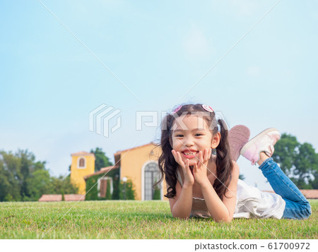 Little Asian cute girl 6 years old lying on the grass and smile at the lawn front of yard. Little Asian cute girl 6 years old lying on the grass and smile at the lawn front of yard. 61700972