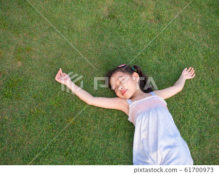 Happy Asian cute girl lying and smiling on the grass at the garden. Happy Asian cute girl lying and smiling on the grass at the garden. 61700973