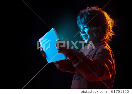Caucasian boy's portrait isolated on dark studio background in neon light Caucasian boy's portrait isolated on dark studio background in neon light 61701300