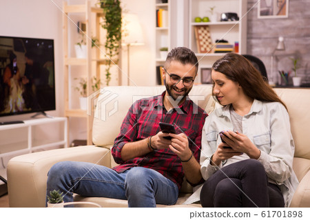 Caucasian man showing something to his girlfriend on the phone 61701898