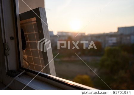 View from inside at solar battery standing on the window of high-rise residential building View from inside at solar battery standing on the window of high-rise residential building 61701984