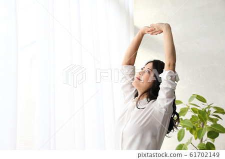A woman who stretches his back at the window and takes a deep breath 61702149