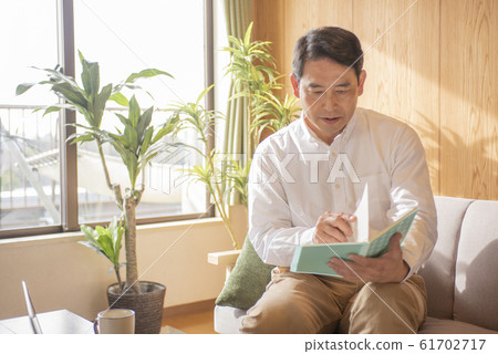Mature man reading a book in the living room Mature man reading a book in the living room 61702717
