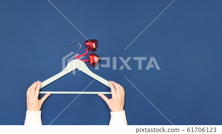 Hands holding hanger with two heart pendants flat Hands holding hanger with two heart pendants flat 61706123