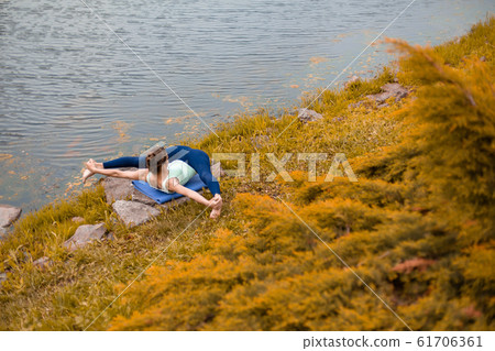 A young sports girl practices yoga on a fall A young sports girl practices yoga on a fall 61706361