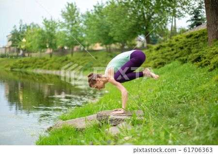 A young sports girl practices yoga on a green lawn A young sports girl practices yoga on a green lawn 61706363