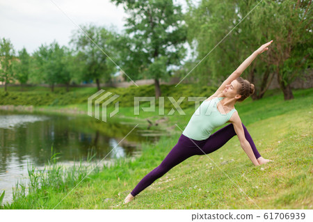 A young sports girl practices yoga on a green lawn A young sports girl practices yoga on a green lawn 61706939