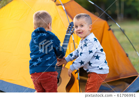 children ask dad to play the guitar. Camping with children ask dad to play the guitar. Camping with 61706991