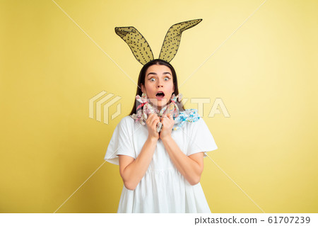 Easter bunny woman with bright emotions on yellow studio background 61707239