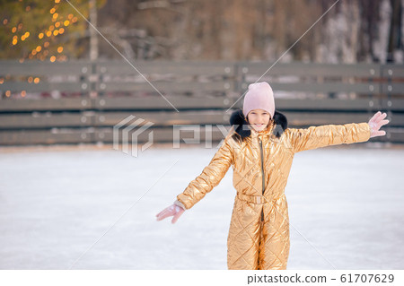 Adorable little girl skating on the ice-rink 61707629