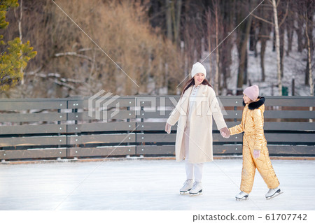 Little adorable girl with her mother skating on ice-rink Little adorable girl with her mother skating on ice-rink 61707742