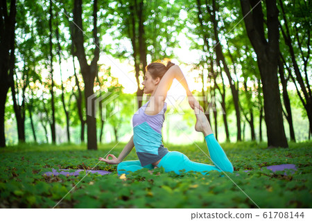 A young sports girl practices yoga in a quit green 61708144