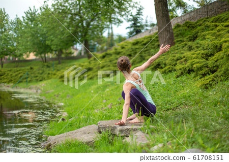 A young sports girl practices yoga on a green lawn A young sports girl practices yoga on a green lawn 61708151