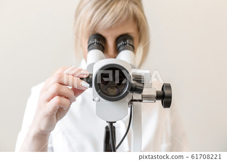 Female blond doctor gynecologist looks through a 61708221