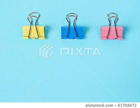 Colorful binder clips on blue paper background. 61708472