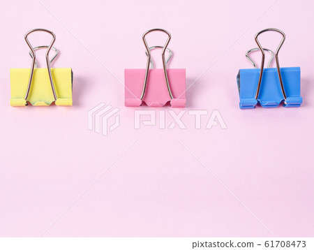 Colorful binder clips on pink paper. Colorful binder clips on pink paper. 61708473