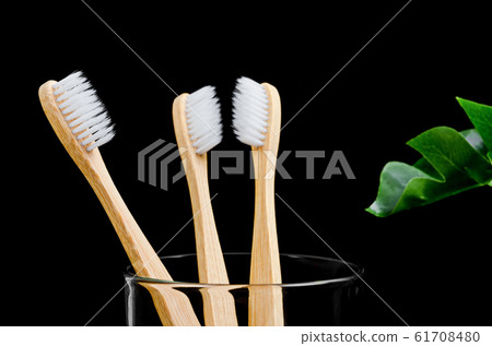 Bamboo toothbrushes with green leaves on black 61708480